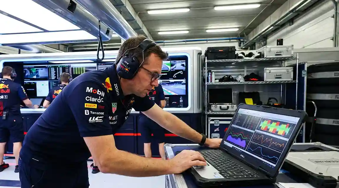 Raceingenieur bestudeert data en grafieken op een laptop in de pitstraat
